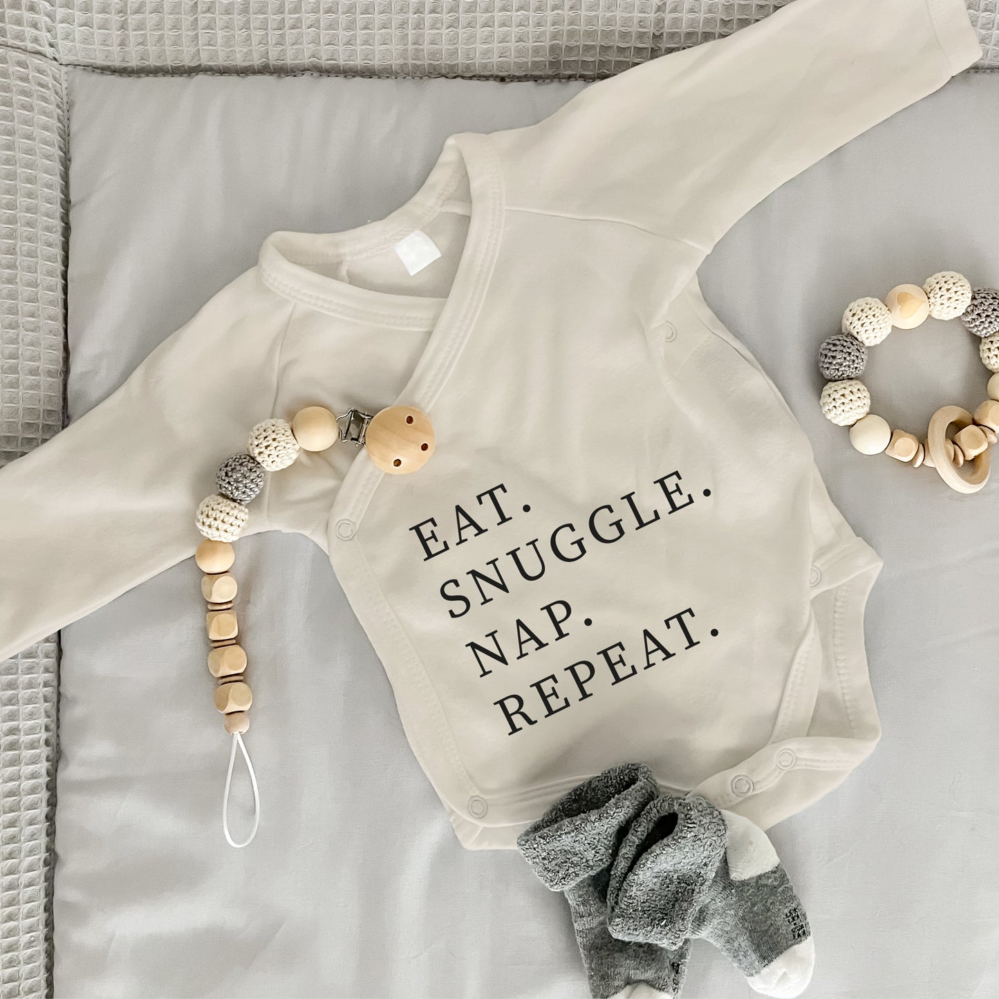 Baby Body Langarm mit Spruch | Wickelbody aus Bio-Baumwolle | Eat. Snuggle. Nap. Repeat.