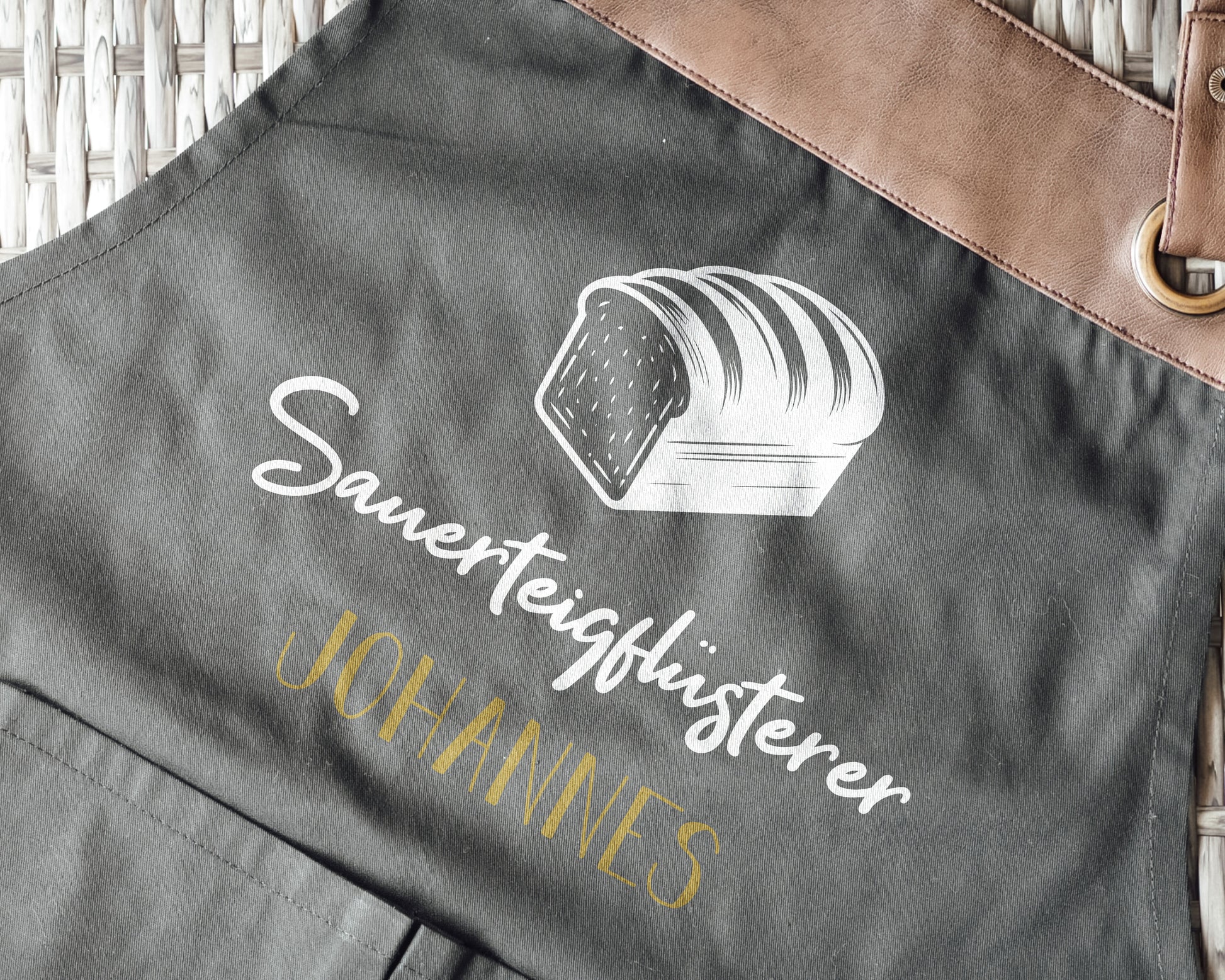 Personalisierte Backschürze mit Kunstleder Applikation „Sauerteigflüsterer“ in Beige oder Schwarz - verschenkich.de