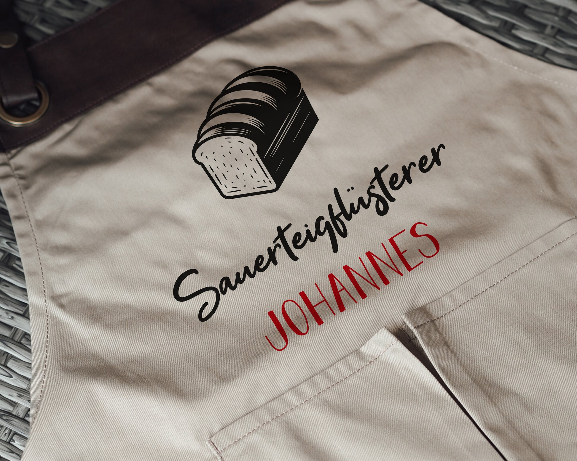 Personalisierte Backschürze mit Kunstleder Applikation „Sauerteigflüsterer“ in Beige oder Schwarz - verschenkich.de