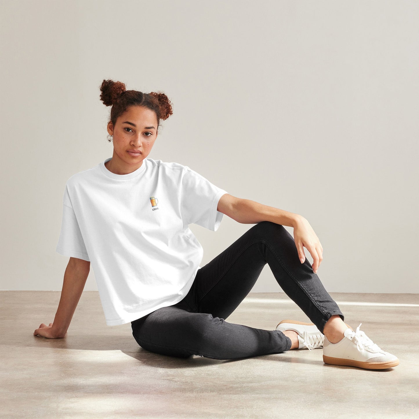 Frau trägt weißes Unisex T-Shirt dem Schriftzug „LIEBE“ mit einer Bierkrug-Illustration auf der linken Brustseite.