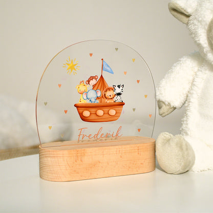 Unbeleuchtetes Nachtlicht mit Acrylplatte und Holzsockel aus Buche im Kinderzimmer, Arche-Noah-Motiv mit Tieren wie Elefant, Giraffe, Zebra, Löwe und Affe, dargestellt in heller Umgebung.