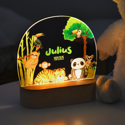 Beleuchtetes Nachtlicht mit Acrylplatte, Dschungelmotiv mit mehreren Tieren sowie dem personalisierten Namen „Julius“ und dem Datum „19.09.2025“, fotografiert im Dunkeln.