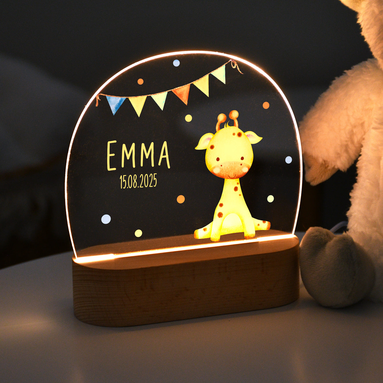 Beleuchtetes Nachtlicht mit Acrylplatte, Giraffenmotiv mit Wimpelgirlande sowie dem personalisierten Namen „Emma“ und dem Datum „15.08.2025“, gezeigt in abgedunkeltem Raum.