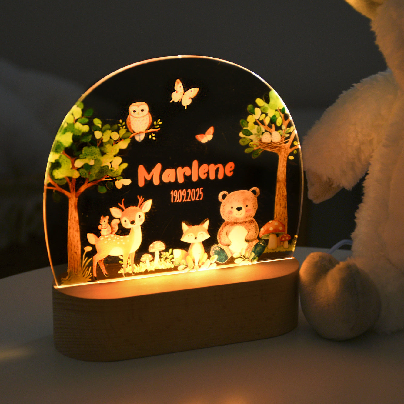 Beleuchtetes Nachtlicht mit Acrylplatte, Waldmotiv mit mehreren Tieren sowie dem personalisierten Namen „Marlene“ und dem Datum „19.09.2025“, fotografiert im Dunkeln.