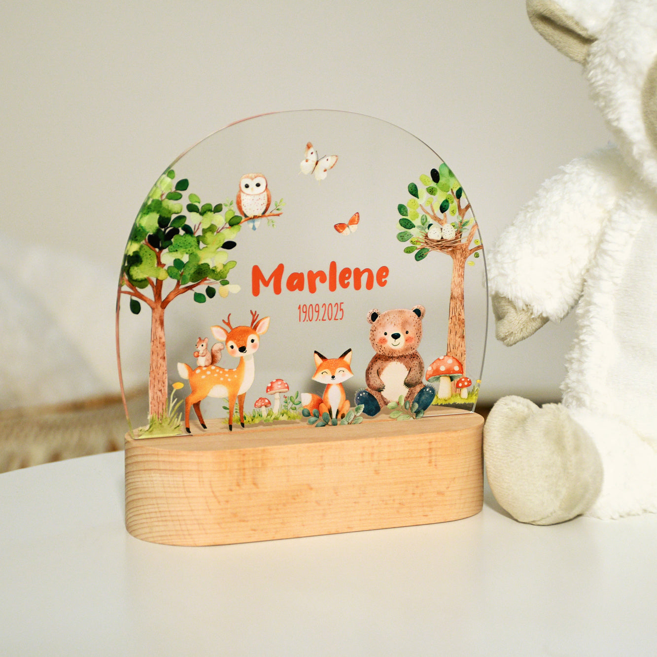 Unbeleuchtetes Nachtlicht mit Acrylplatte und Holzsockel aus Buche im Kinderzimmer, Waldmotiv mit Tieren wie Bär, Fuchs, Reh, Eichhörnchen und Eule, fotografiert in heller Umgebung.