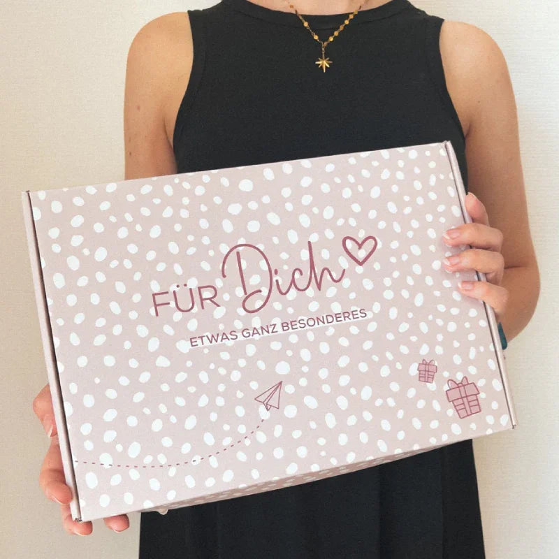 Frau hält verschenkich Textil Geschenkbox mit Aufschrift "Für Dich", Etwas ganz Besonderes. Box mit Geschenk Symbolen und Herz