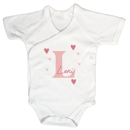Weißer Wickelbody mit kurzem Arm, rosa Initiale „L“, Name „Leni“ und Herzmotiven auf weißem Hintergrund.