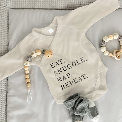 Baby Body Langarm mit Spruch | Wickelbody aus Bio-Baumwolle | Eat. Snuggle. Nap. Repeat.