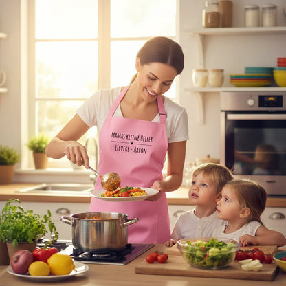 Mutter mit rosa personalisierter Schürze kocht mit zwei Kindern in heller Küche