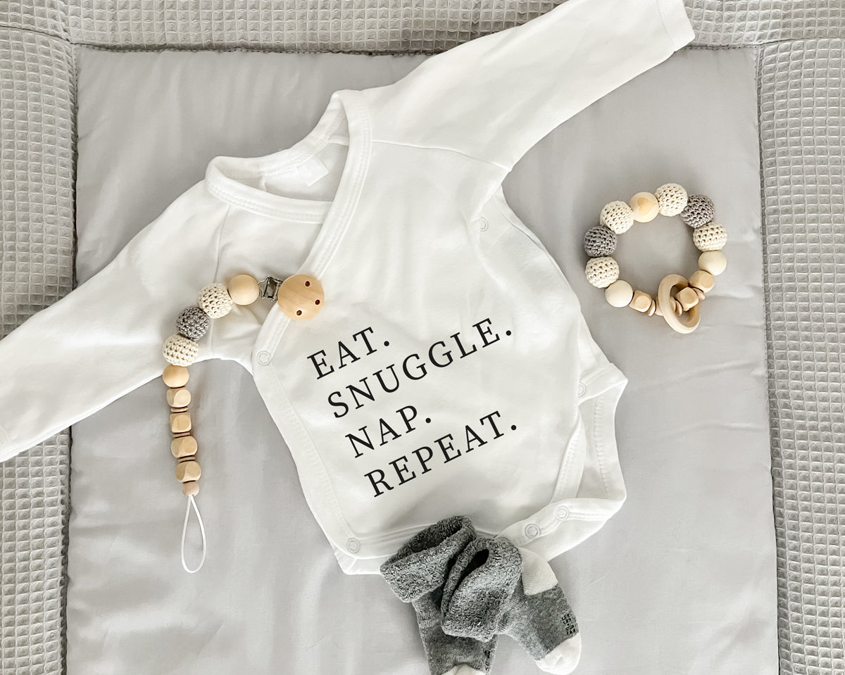 Premium Wickelbody | Spruch | Eat. Snuggle. Nap. Repeat | Langarm Body | Bio-Baumwolle | Geschenk zur Geburt mit Humor - verschenkich.de