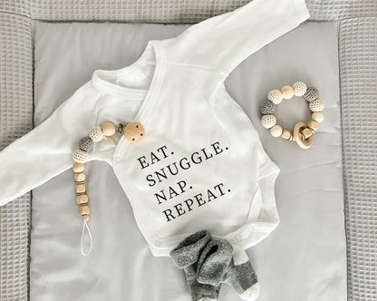 Premium Wickelbody | Spruch | Eat. Snuggle. Nap. Repeat | Langarm Body | Bio-Baumwolle | Geschenk zur Geburt mit Humor - verschenkich.de