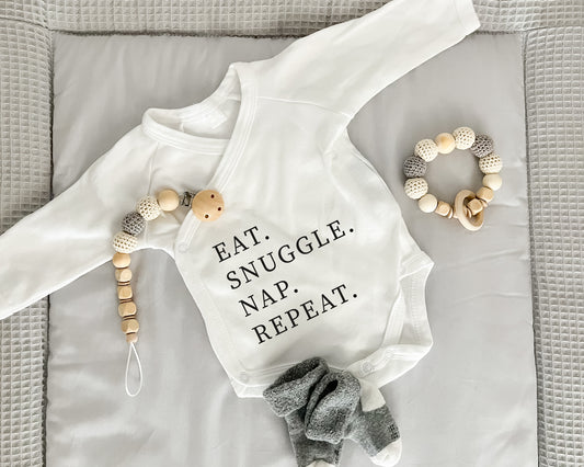 Premium Wickelbody | Spruch | Eat. Snuggle. Nap. Repeat | Langarm Body | Bio-Baumwolle | Geschenk zur Geburt mit Humor - verschenkich.de