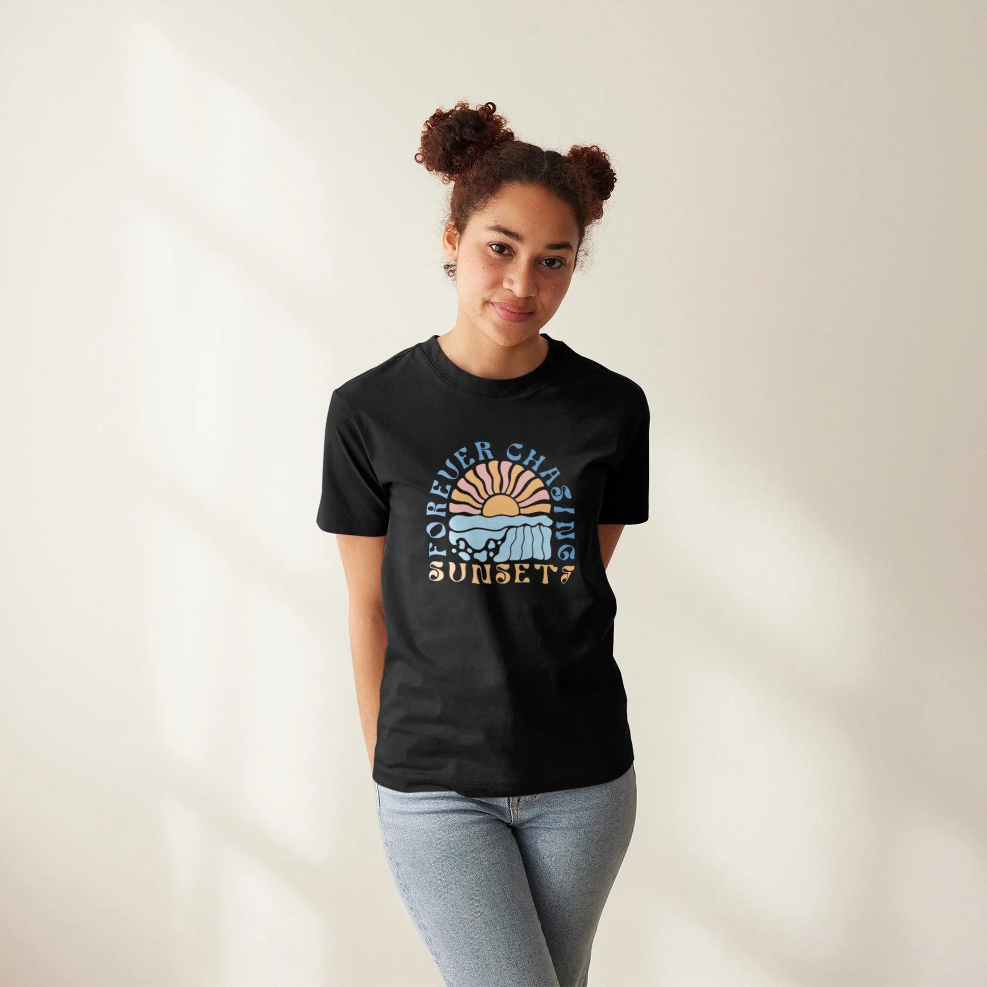 Frau trägt schwarzes T-Shirt mit farbigem Sonnenuntergangs-Print und Aufschrift "Forever Chasing Sunset"